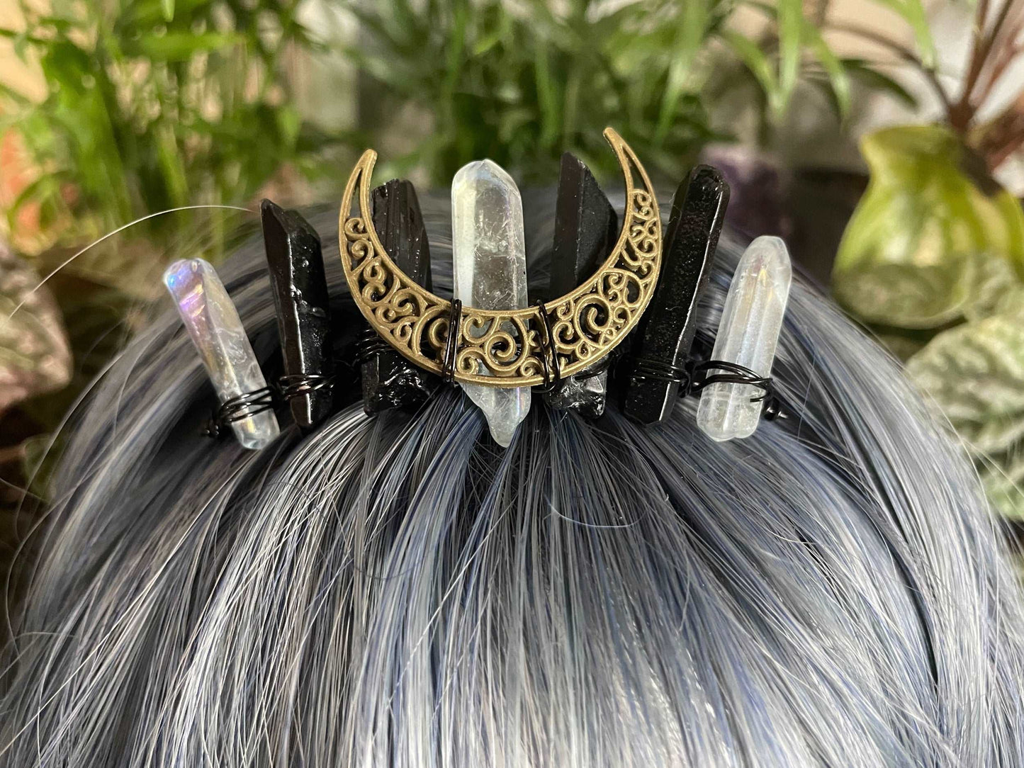 Pictured is a hair comb with clear quartz and obsidian crystal points and a gold coloured crescent moon in the middle.