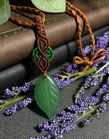 Pictured is a green aventurine cabochon wrapped in macrame thread. A gothic book and flowers are nearby.