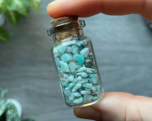 An image of a small glass vial with a cork stopper. Amazonite chips are inside.