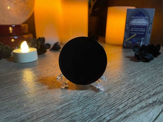 Pictured is a scrying mirror on a stand. The scrying mirror is carved out of black obsidian.