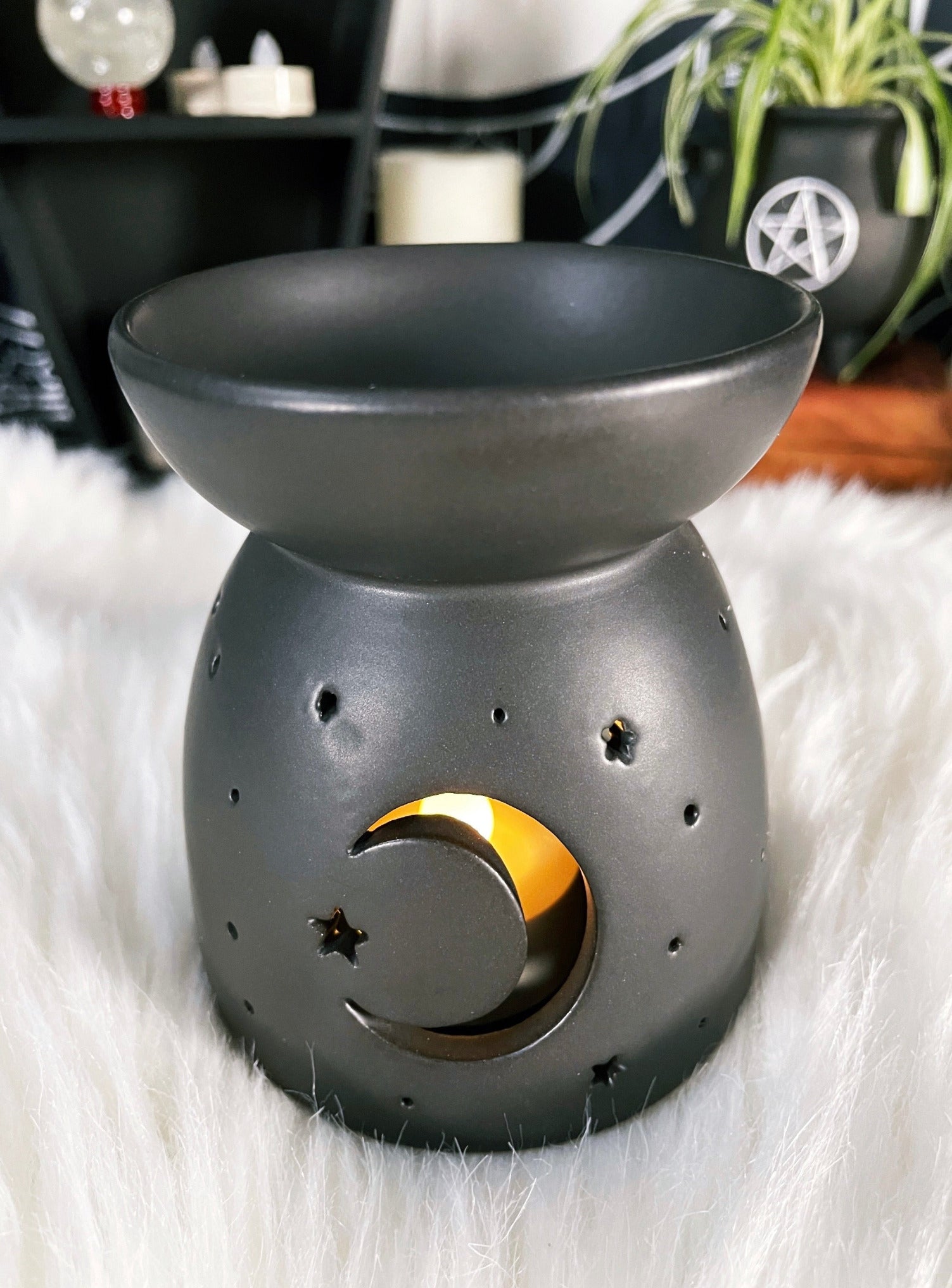 A black ceramic oil burner / wax melt burner with a crescent moon design cut out.