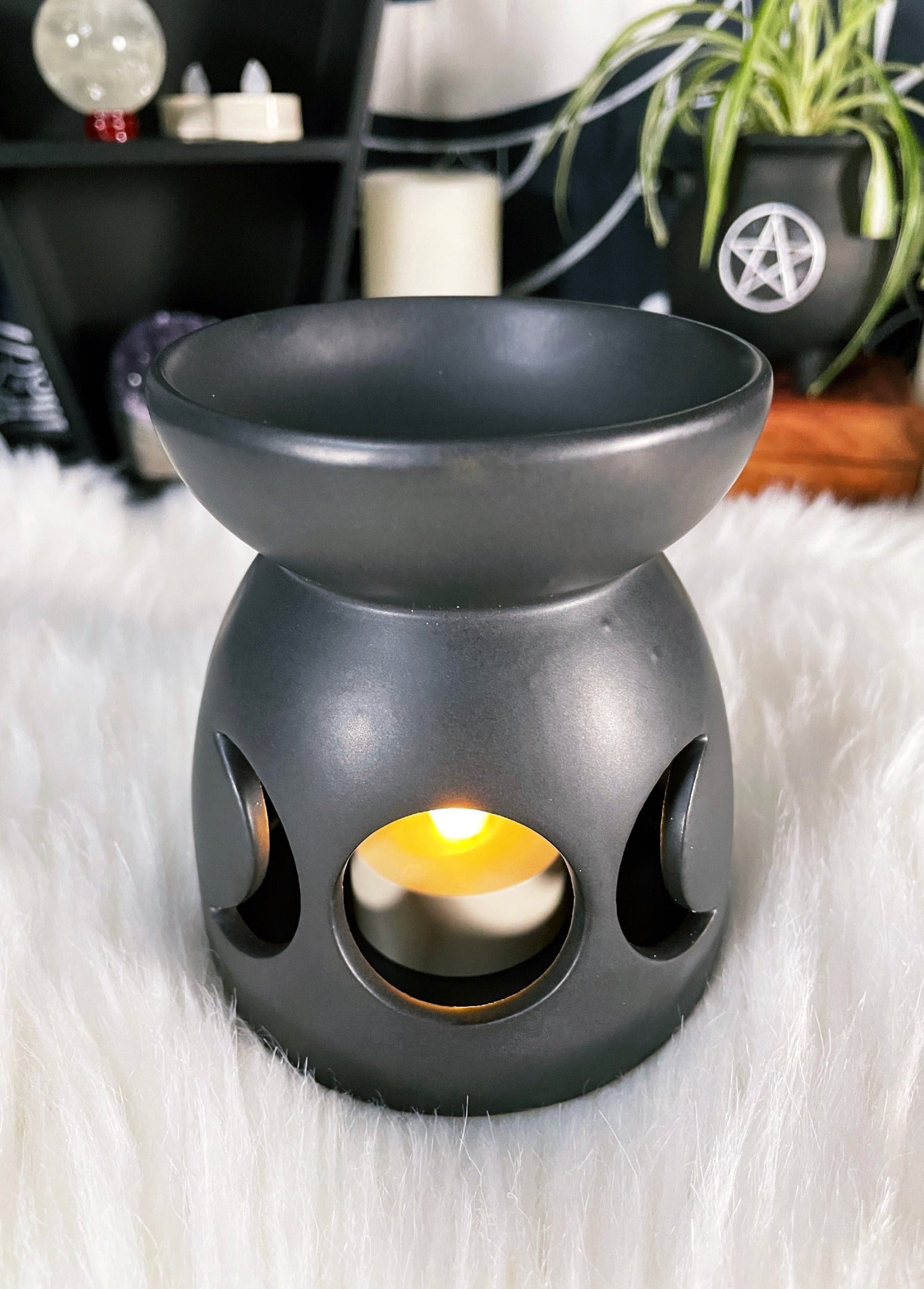 A black ceramic oil burner / wax melt burner with a triple moon design cut out.