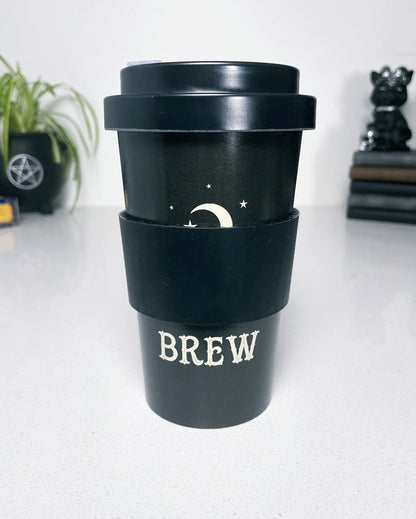 A black eco travel mug with a white words that say "Witches Brew" on the side. 