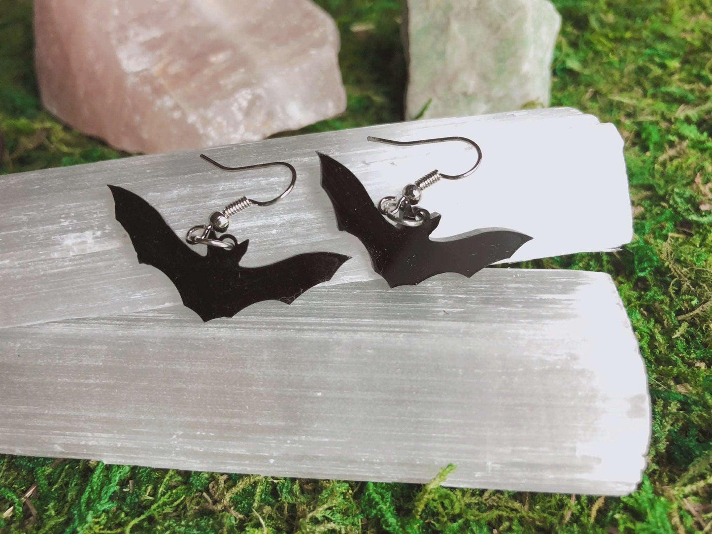 Pictured is a pair of black bat earrings made of acrylic. 