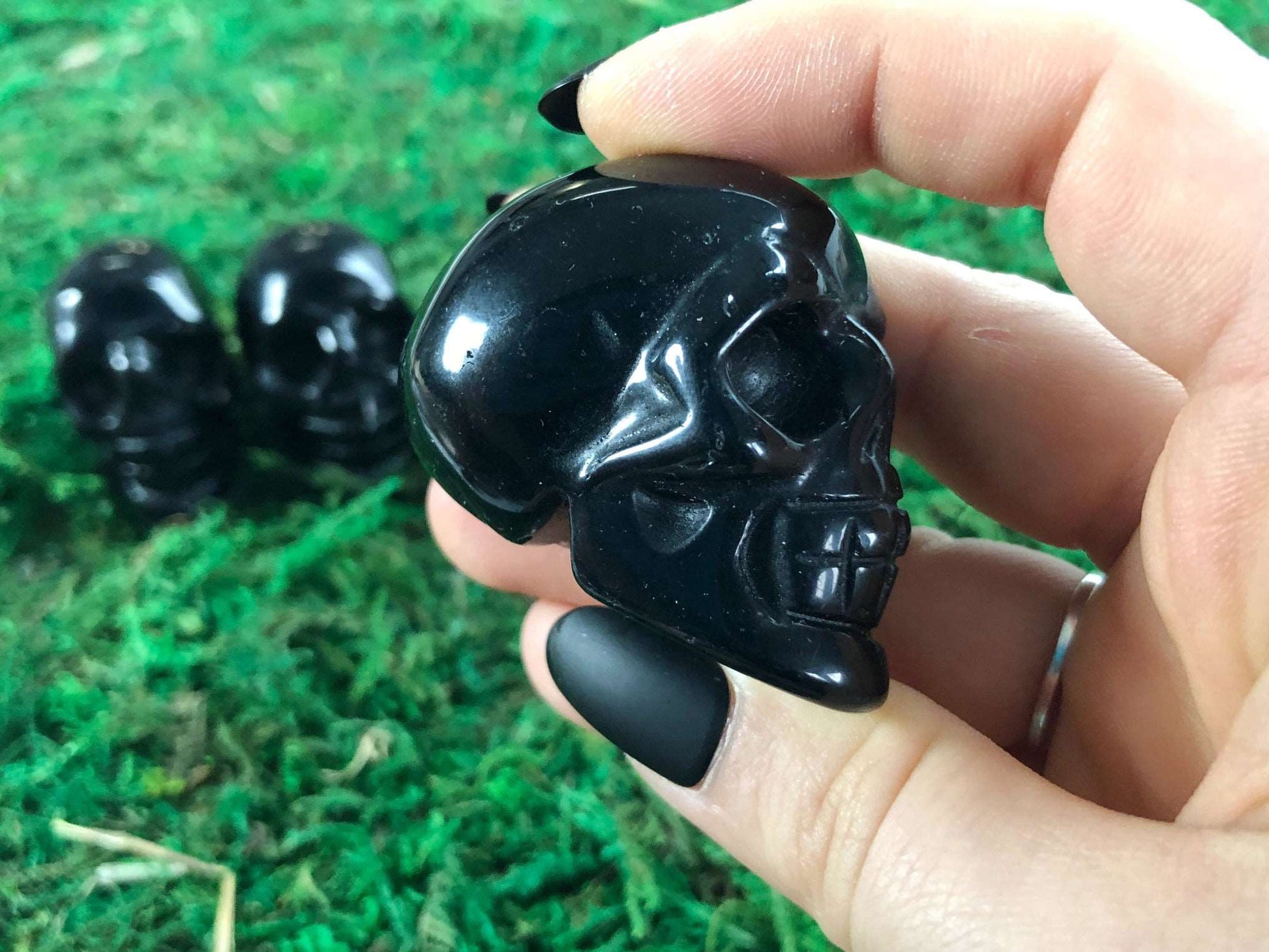 Pictured are various two inch skulls carved out of black obsidian.