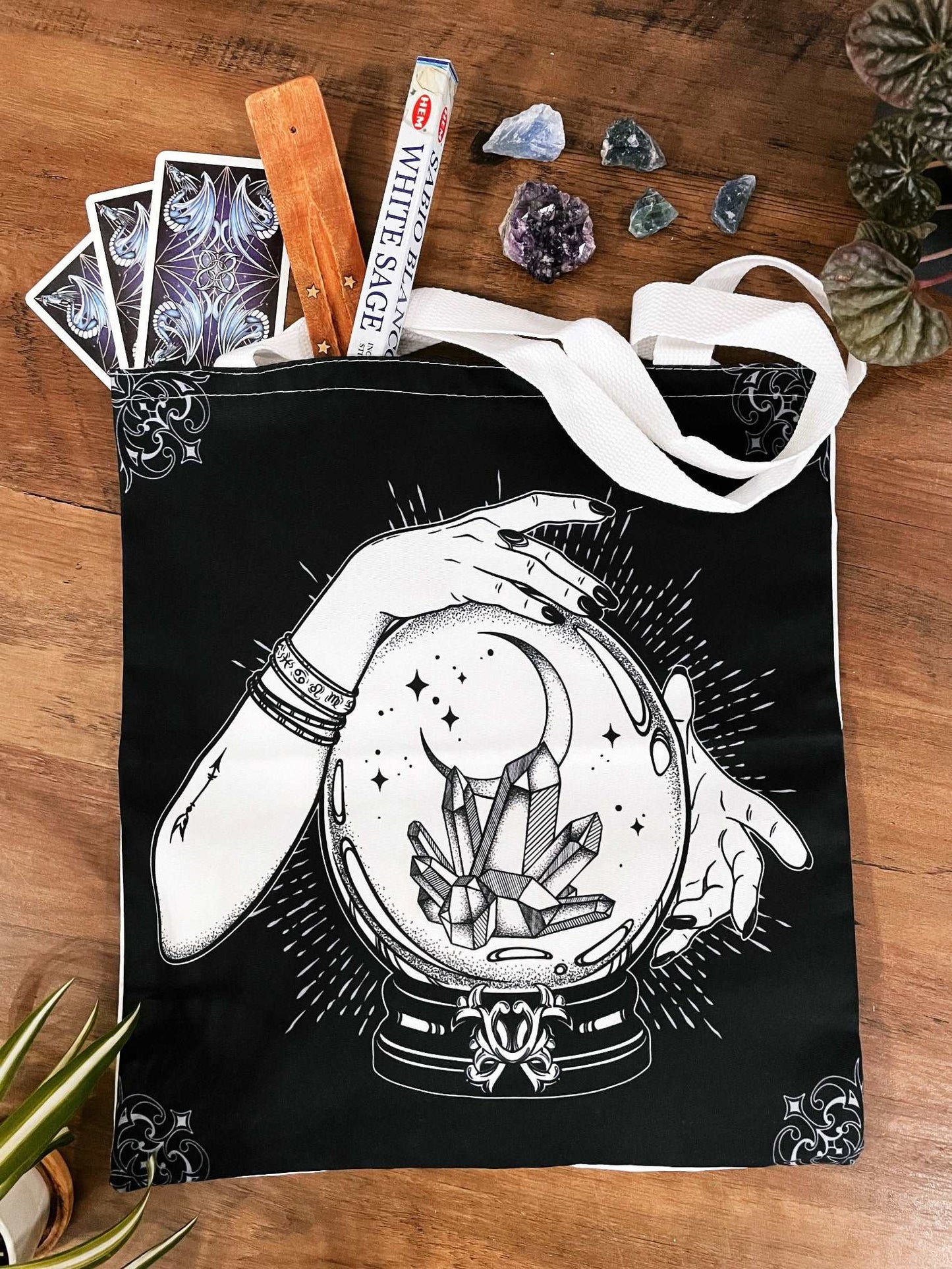 Pictured is a large canvas tote bag featuring an image of two hands around a crystal ball with crystals inside.