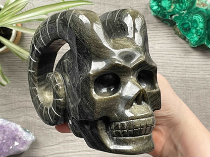 Pictured is a large demon skull with horns carved out of gold sheen obsidian.