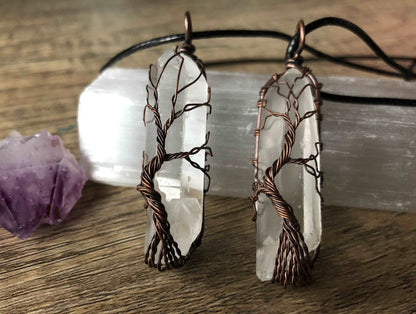 An image of a necklace featuring a wire-wrapped pendant. The wire is in the shape of a tree and it is wrapped around a quartz point.