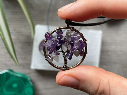 An image of a necklace featuring a wire-wrapped pendant. The wire is in the shape of a tree and the leaves on the tree are polished chips of amethyst.