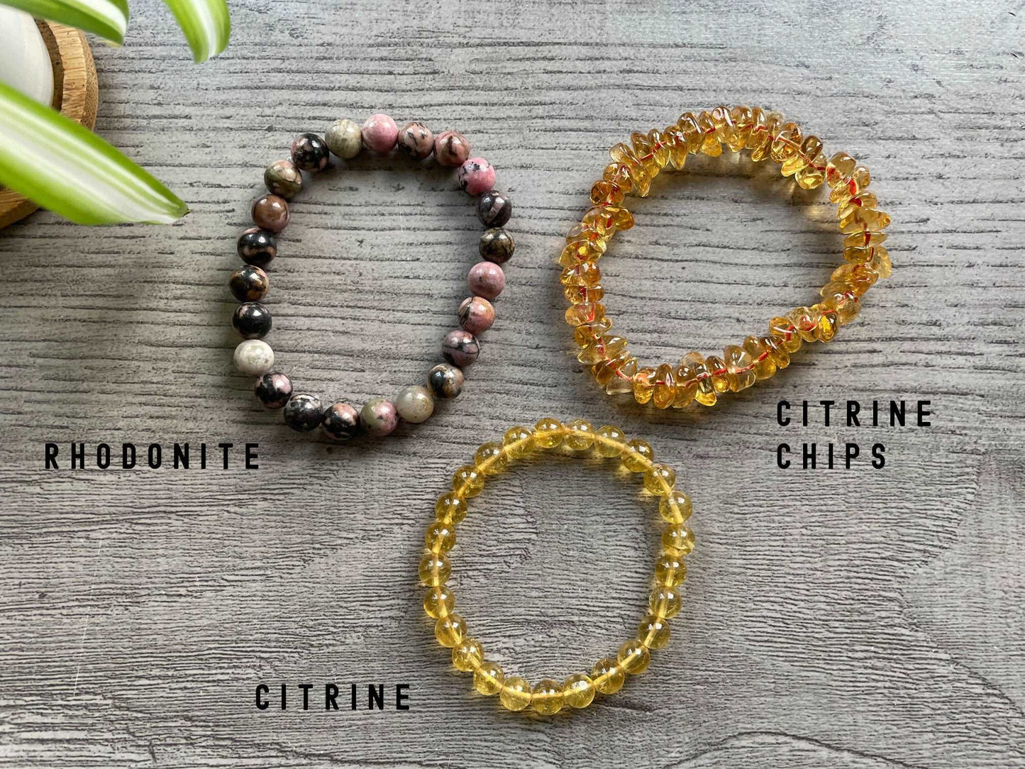 Pictured is a rhodonite bead bracelet, a citreine chip bracelet, and a citrine bead bracelet.
