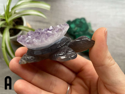 A grey agate turtle carving with purple amethyst crystals on its shell.