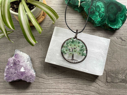 An image of a necklace featuring a wire-wrapped pendant. The wire is in the shape of a tree and the leaves on the tree are polished chips of green aventurine.