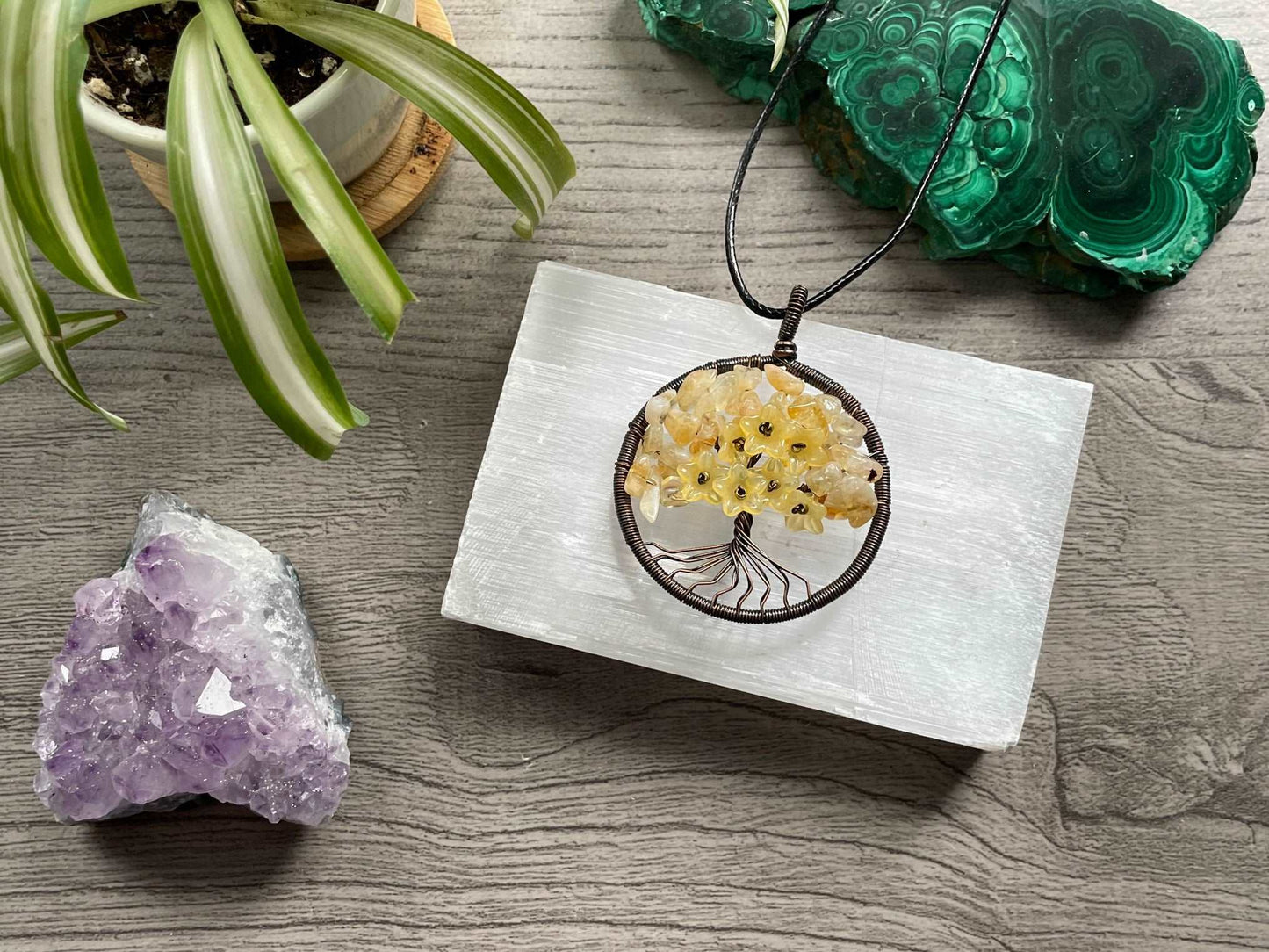 An image of a necklace featuring a wire-wrapped pendant. The wire is in the shape of a tree and the leaves on the tree are polished chips of citrine.