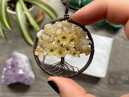 An image of a necklace featuring a wire-wrapped pendant. The wire is in the shape of a tree and the leaves on the tree are polished chips of citrine.