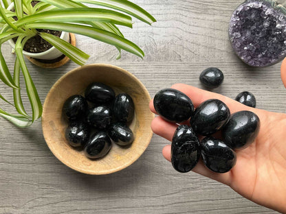 Pictured are various black tourmaline tumbled stones.