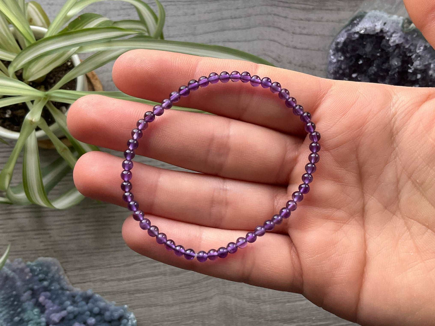A close-up image of a bracelet made of smooth, round beads in a deep shade of purple. The beads are all the same size and made of amethyst, a type of quartz crystal known for its beautiful color and spiritual properties.