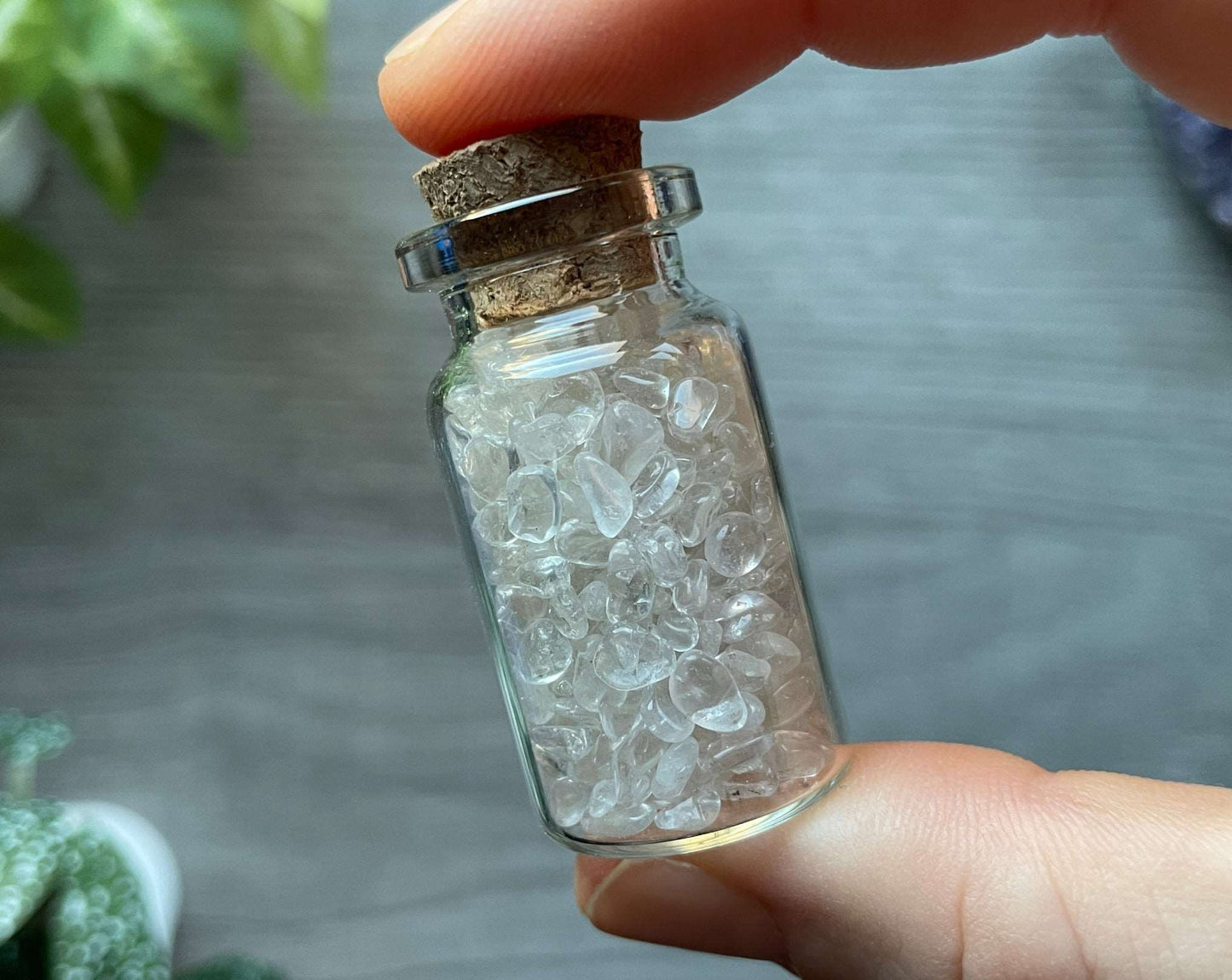 Pictured is a small glass vial with a cork stopper. Inside the jar are quartz chips.