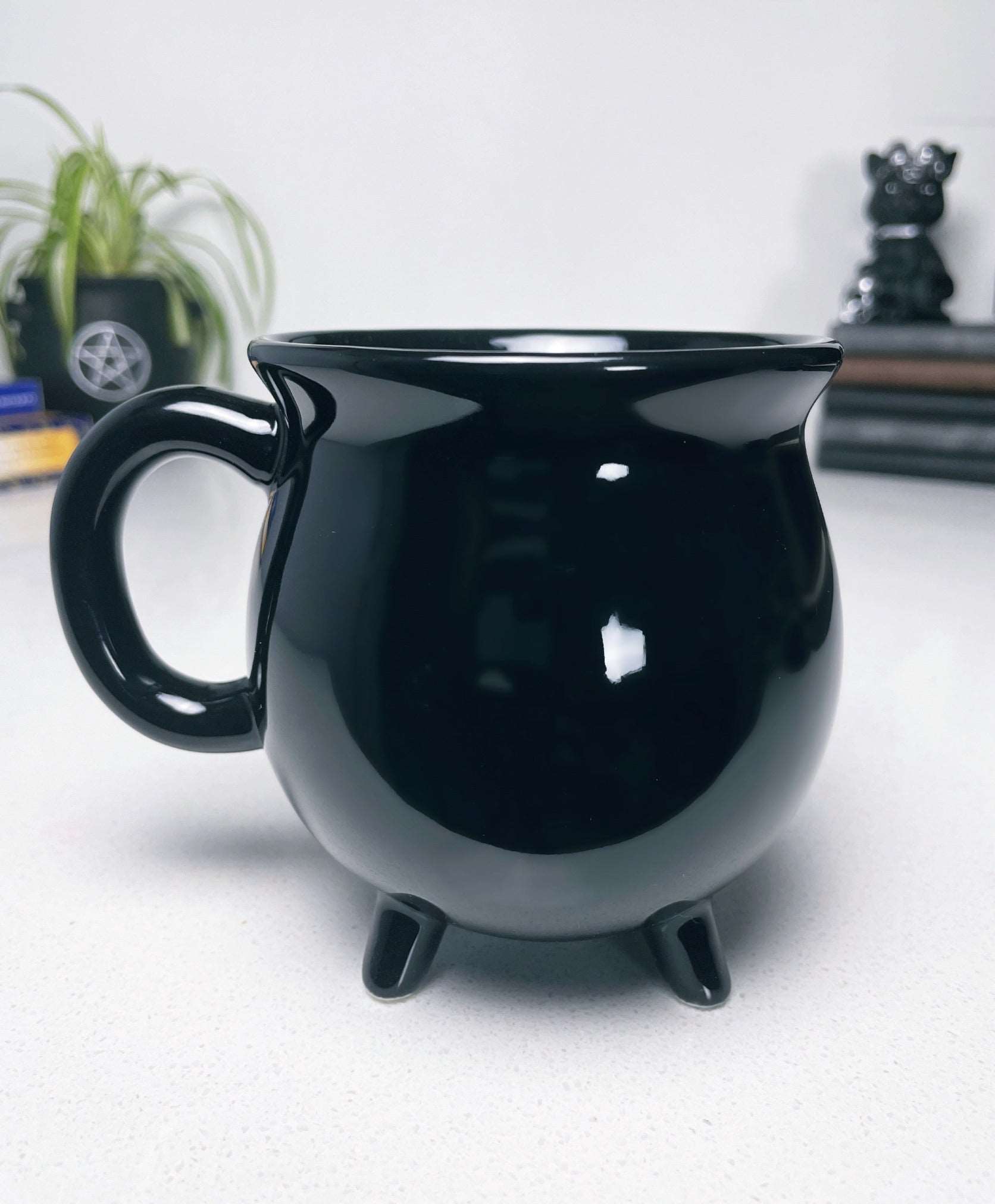 Pictured is a black ceramic mug in the shape of a cauldron.