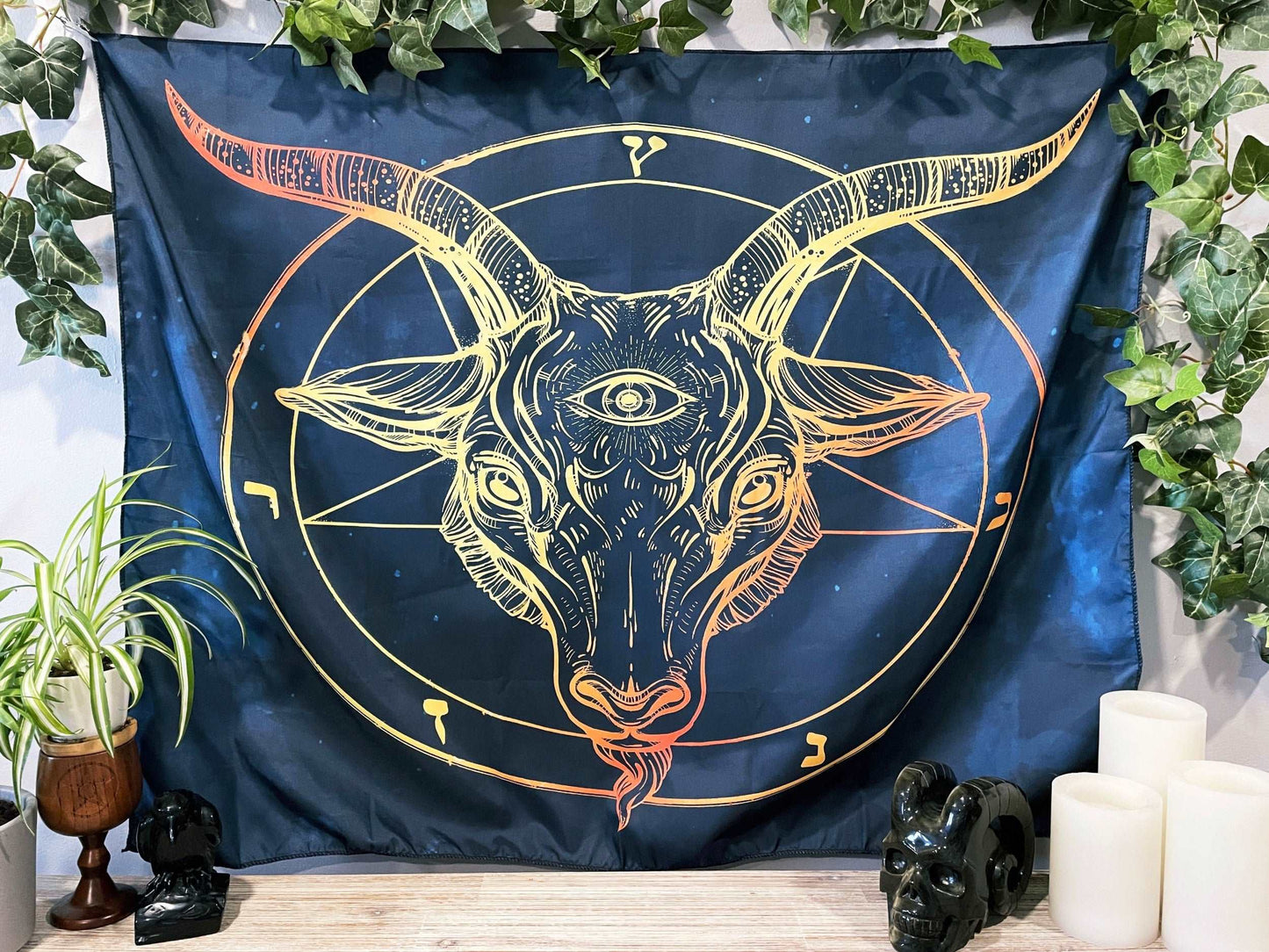 Pictured is a large wall tapestry with a dark blue background and an image of baphomet printed in yellow and orange.