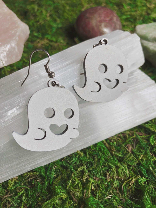 Pictured is a pair of earrings featuring a cute white ghost. They are made of wood. 
