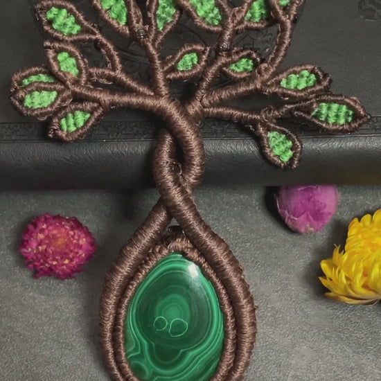A handmade macrame necklace featuring a tree design with a malachite cabochon as its centerpiece.