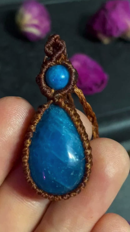 Pictured is a blue apatite cabochon wrapped in macrame thread. A gothic book and flowers are nearby.