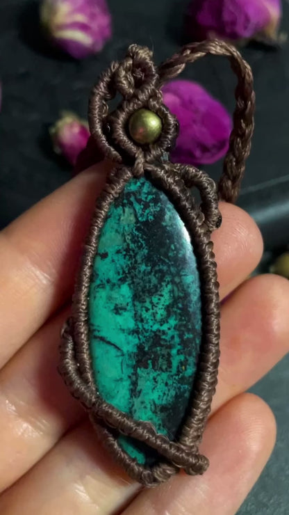 Pictured is a chrysocolla cabochon wrapped in macrame thread. A gothic book and flowers are nearby.