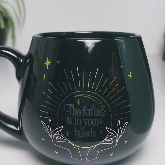 Pictured is a black ceramic mug with colour-changing words that say "The future is in your hands".