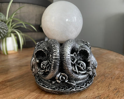 Pictured is a sphere stand in the shape of goat skulls ram skulls.