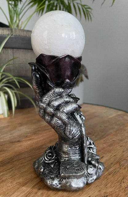 Pictured is a sphere stand in the shape of a hand holding a rose.