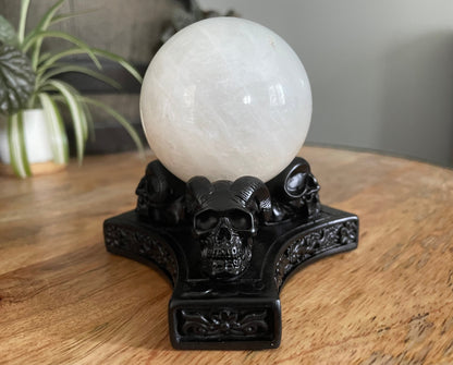 Pictured is a sphere stand in the shape of three demon skulls.