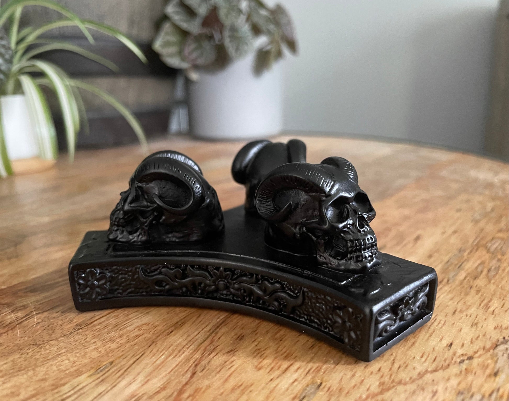 Pictured is a sphere stand in the shape of three demon skulls.