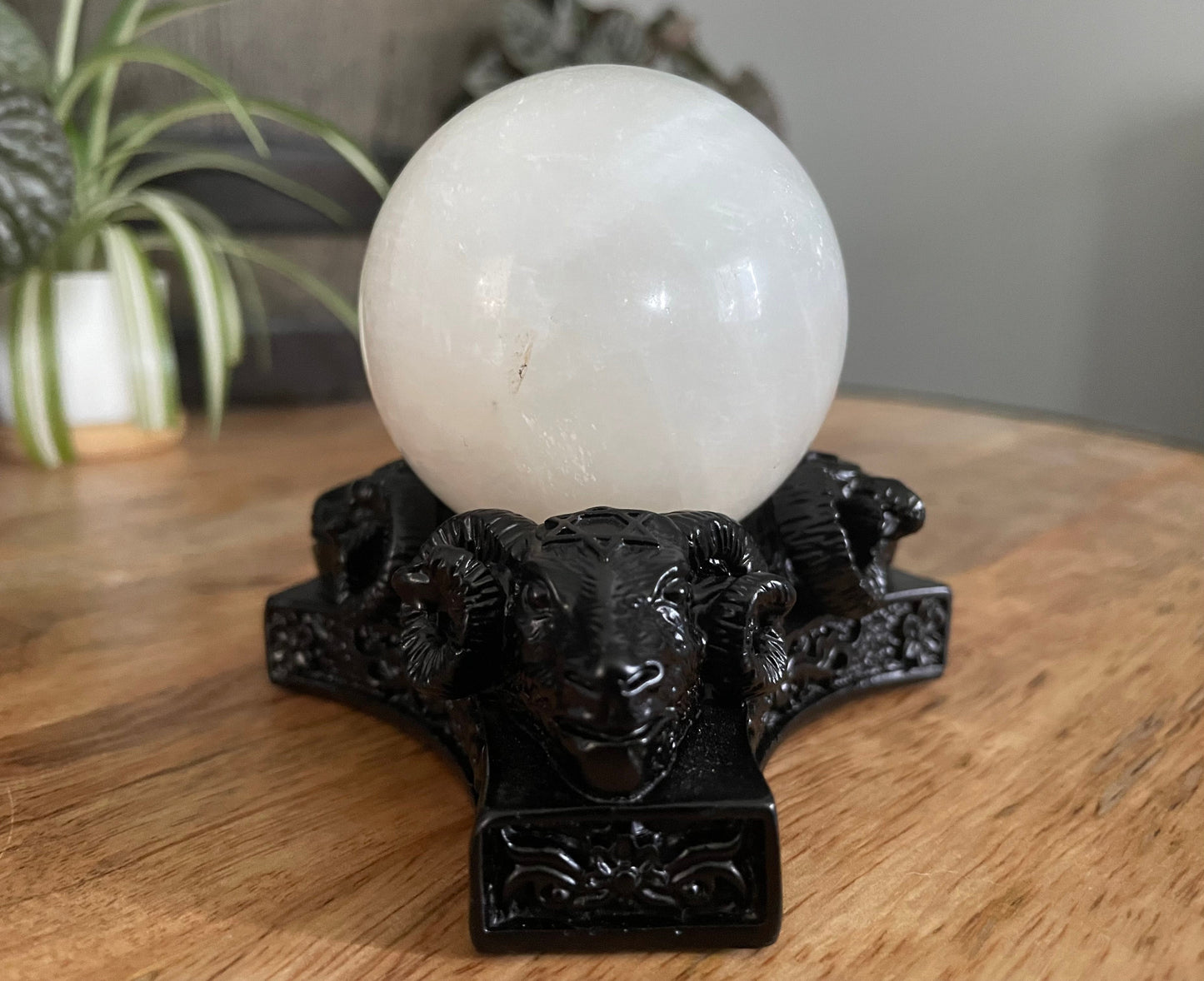 Pictured is a sphere stand in the shape of three ram skulls or goat skulls.