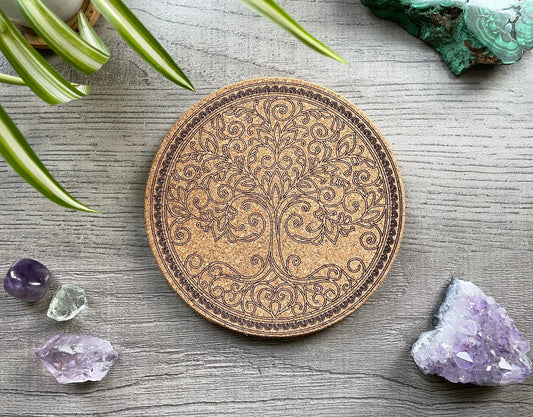 Pictured is a cork trivet with a tree of life design on it.