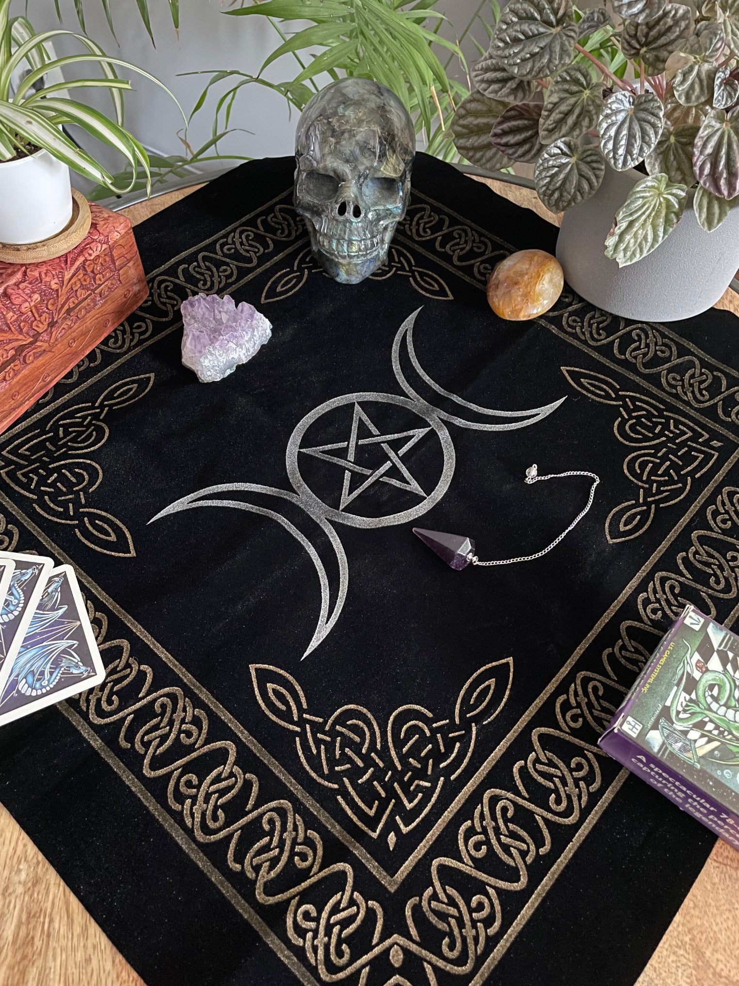 Pictured is a black velvet altar cloth with a silver pentacle and triple moon symbol in the middle.