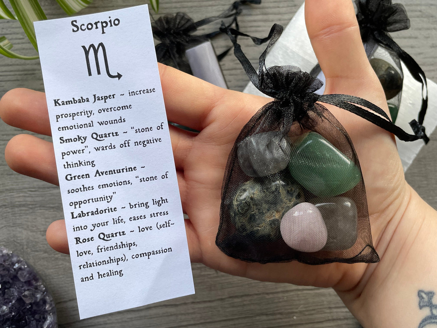 An image of a collection of tumbled stones in an organza bag. To the side is a piece of paper that describes what each tumbled stone's metaphysical properties are.