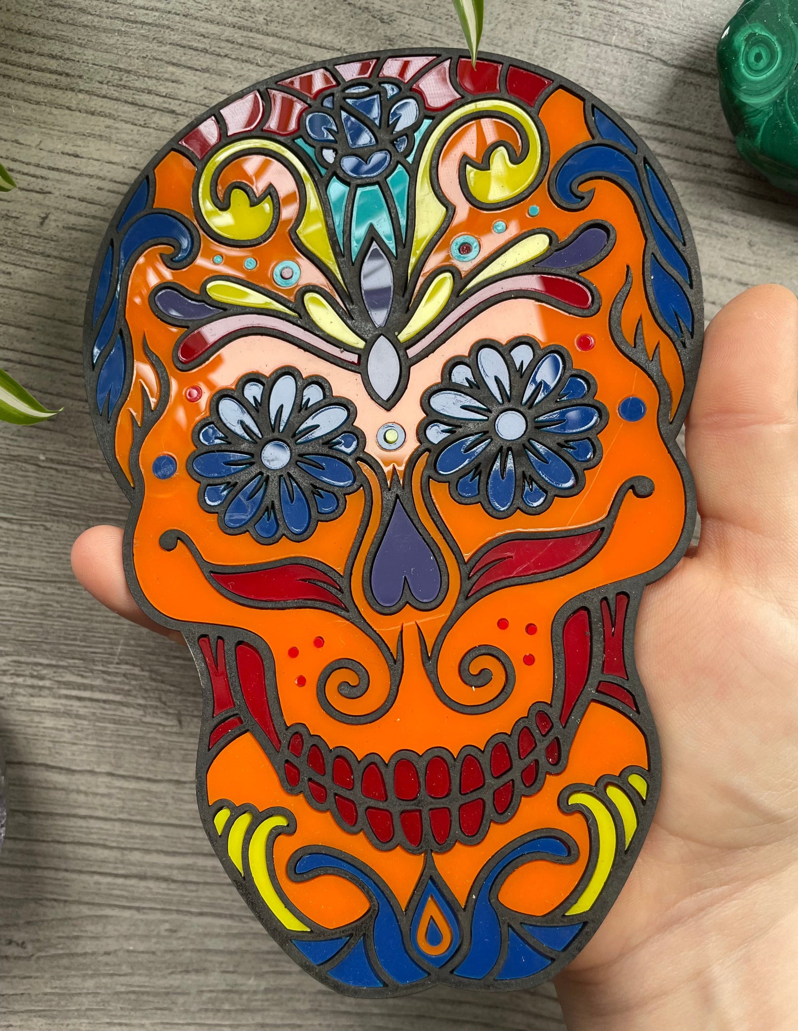 Pictured is a faux stained glass sugar skull made out of wood and acrylic.