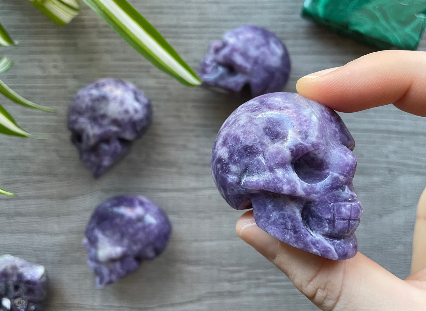 Pictured are various skulls carved out of lepidolite.