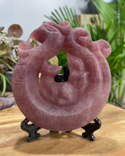 Pictured is a nine-tailed fox sitting on a phoenix carved out of strawberry quartz.