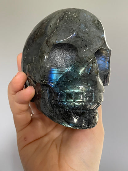 Pictured is a large skull carved out of labradorite with blue and green and yellow flashes..