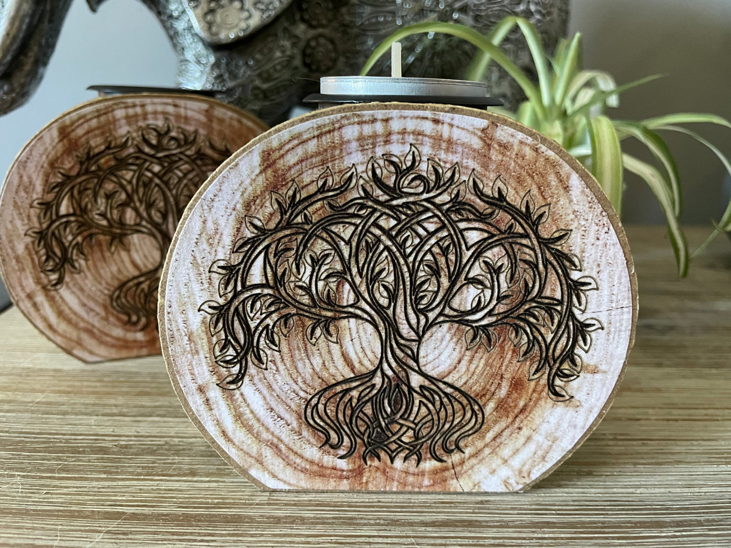 Pictured is a wood tree slice candle holder with a tree of life envraged on it.