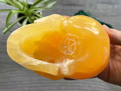 Pictured is a large skull carved out of orange calcite.