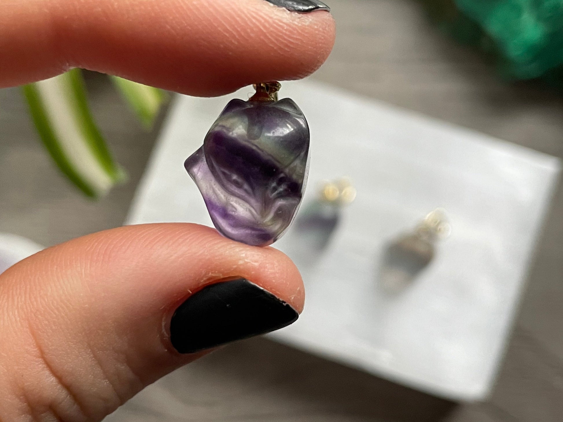 Pictured is a rainbow fluorite charm pendant in the shape of a cute fox.