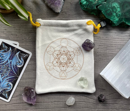 Pictured is a cream-coloured, faux-suede drawstring bag with a sacred geometry symbol printed on the front.