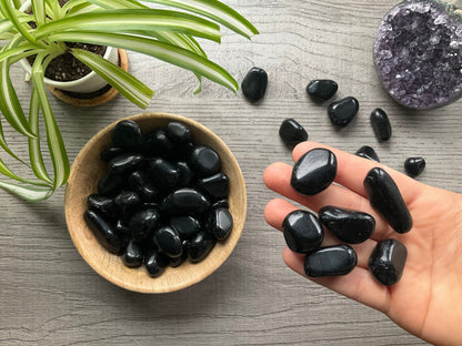 Pictured are various black obsidian tumbled stones.