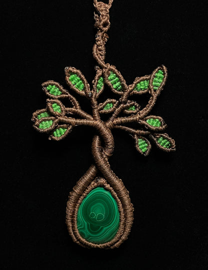 A handmade macrame necklace featuring a tree design with a malachite cabochon as its centerpiece.