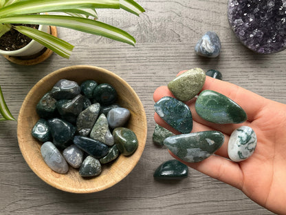 Pictured are various moss agate tumbled stones.