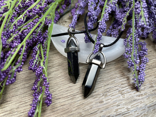 An image of hematite double-terminated polished crystal necklaces sitting on selenite and surrounded by lavender on a wood surface..