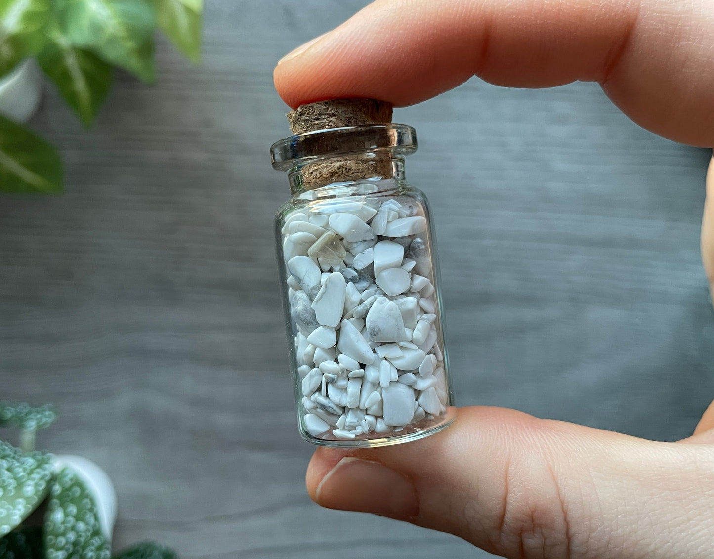 Pictured is a small glass vial with a cork stopper. Inside the jar are howlite chips.