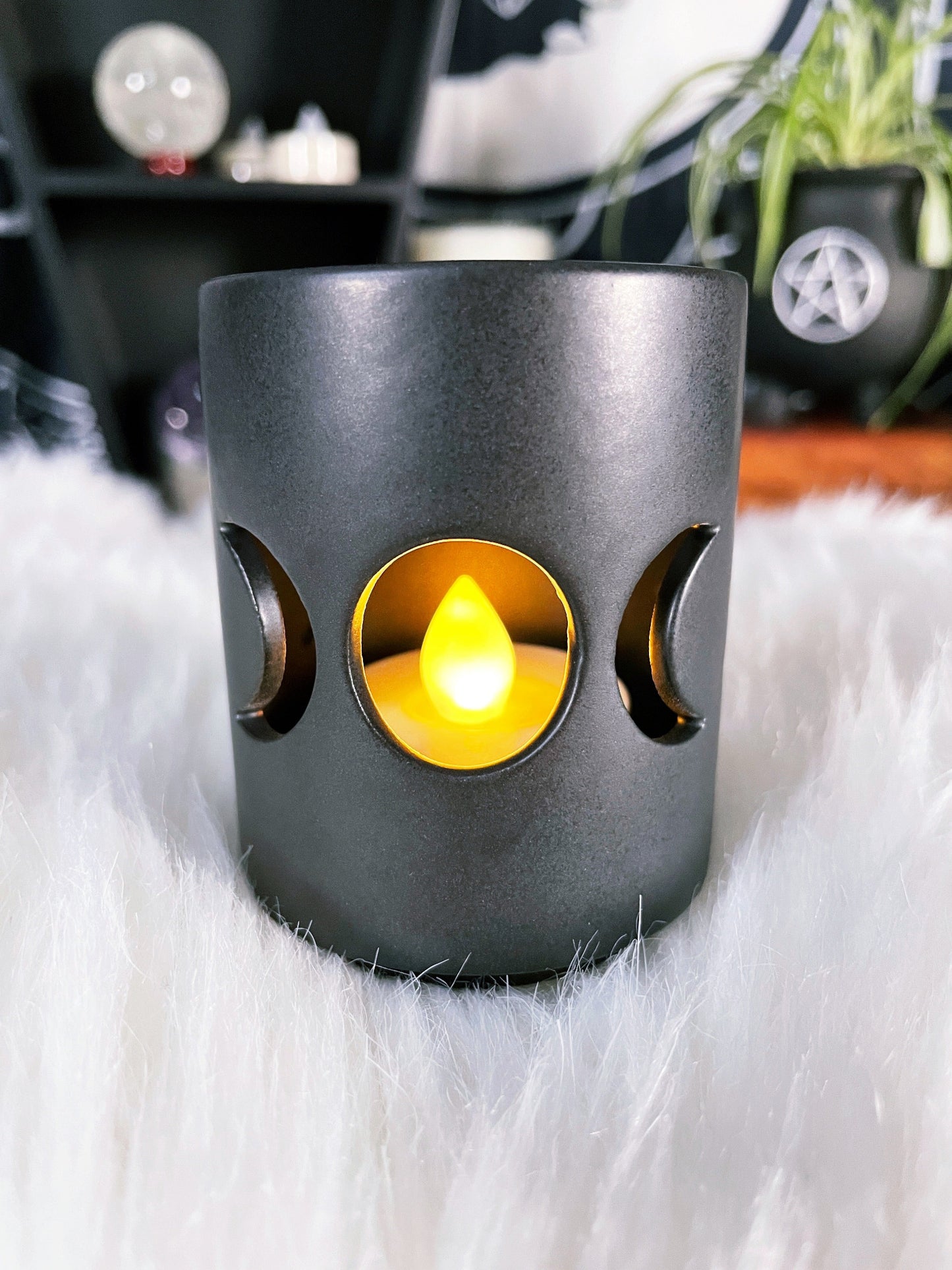 A black ceramic tealight holder with a triple moon design cut out.